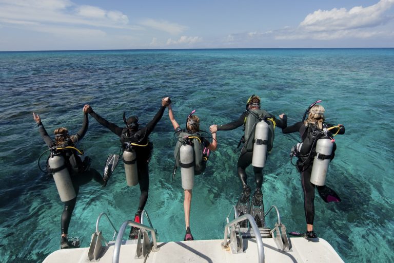 Scuba divers enter water from boat via giant stride entry.,Diving into the water.