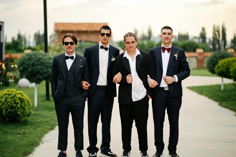 men in button-down shirts and dark jeans standing outside an upscale nightclub