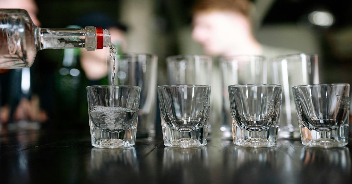 Group of friends laughing and drinking at a crowded bar during a bachelor party
