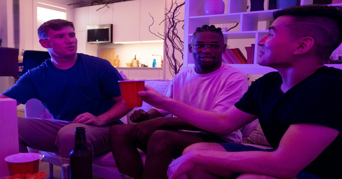 Group of men laughing together in a bright living room during a bachelor party