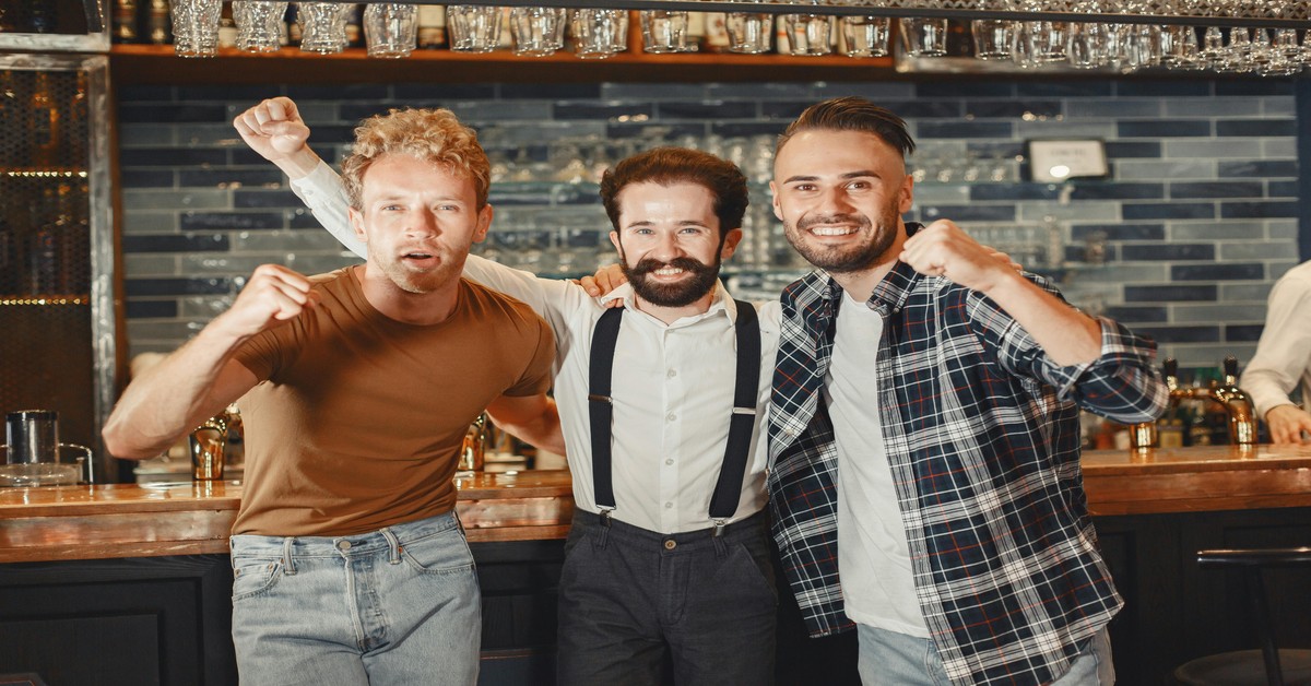 Group of men laughing and raising glasses at a bachelor party celebration