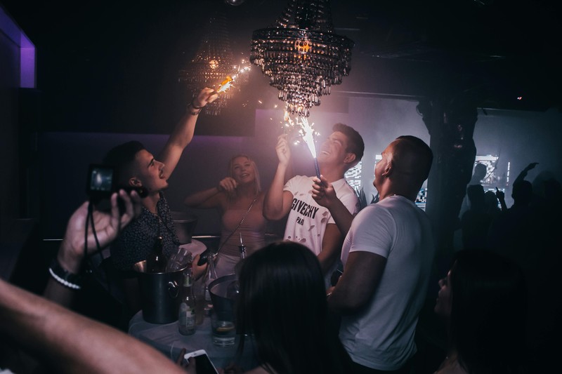 group of men seated in a VIP section of a strip club with bottle service