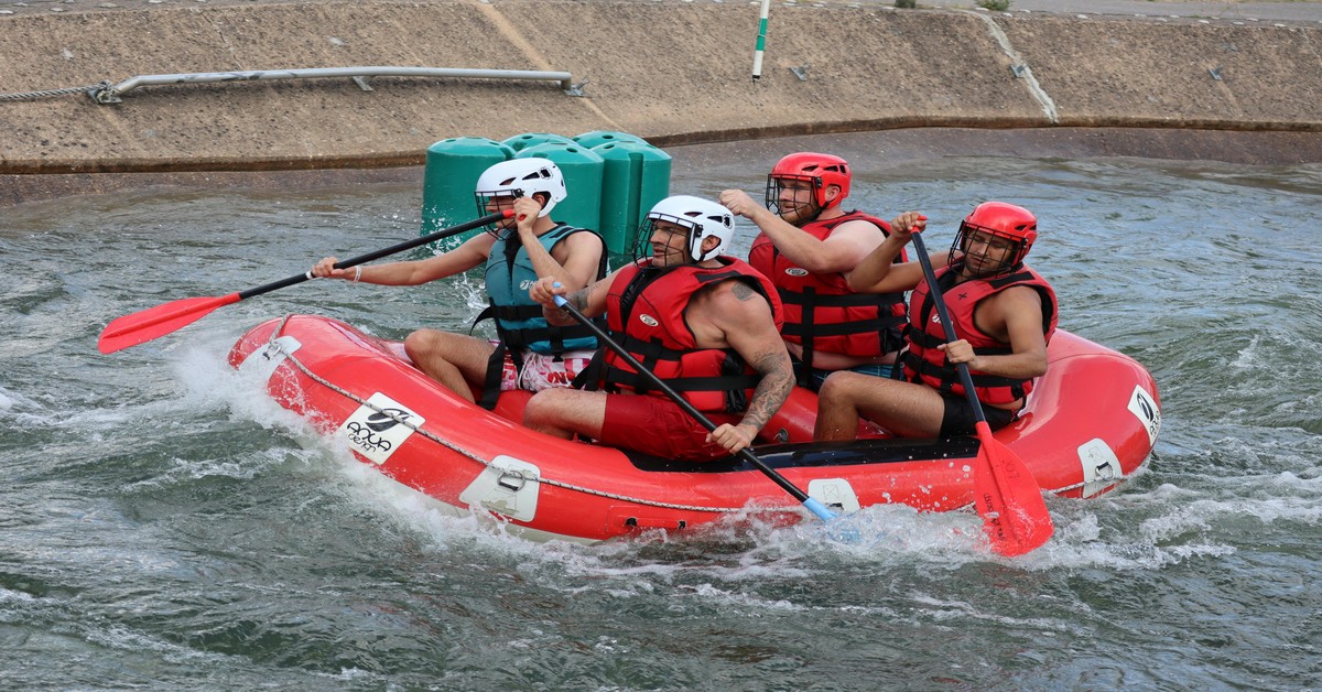 Group of men whitewater rafting on a river during a bachelor party daytime adventure