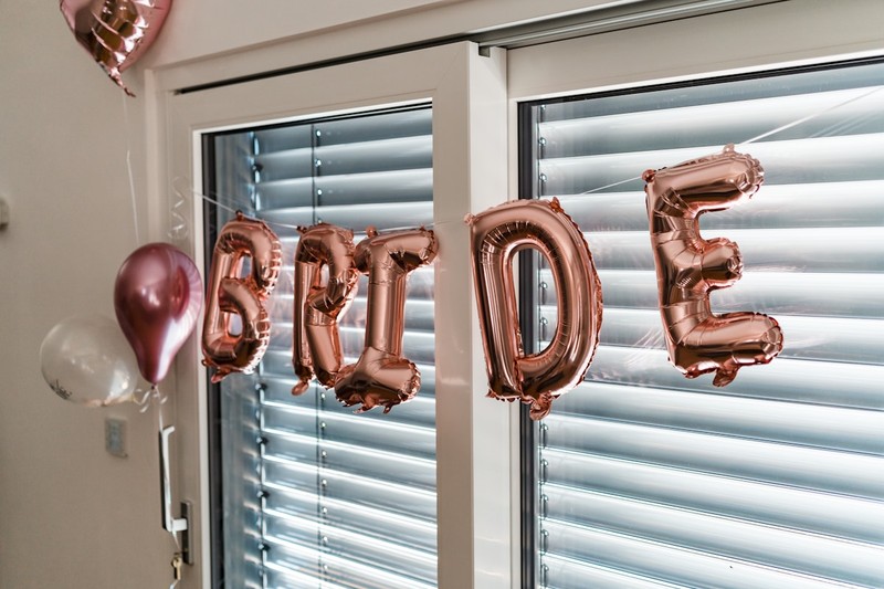 A group of women posing in front of a balloon arch at a bachelorette party