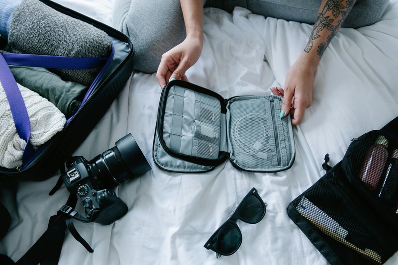Open suitcase on a hotel bed neatly organized with packing cubes, a portable charger, and a tote bag