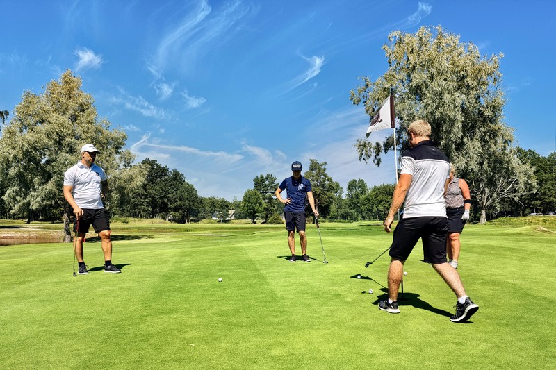 Four men in golf attire standing on a tee box overlooking a desert golf course in Scottsdale