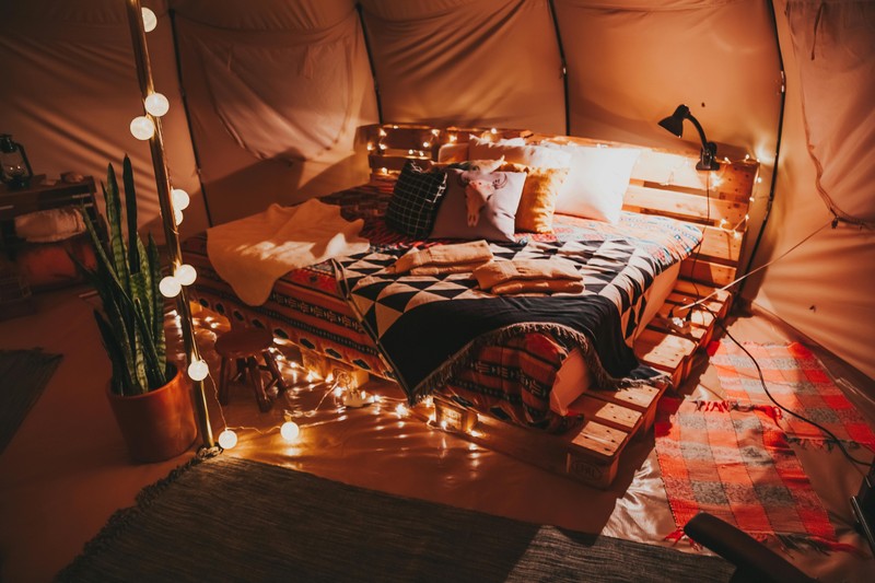 A luxurious glamping tent interior with fairy lights, bedding, and cozy decor for a bachelorette getaway