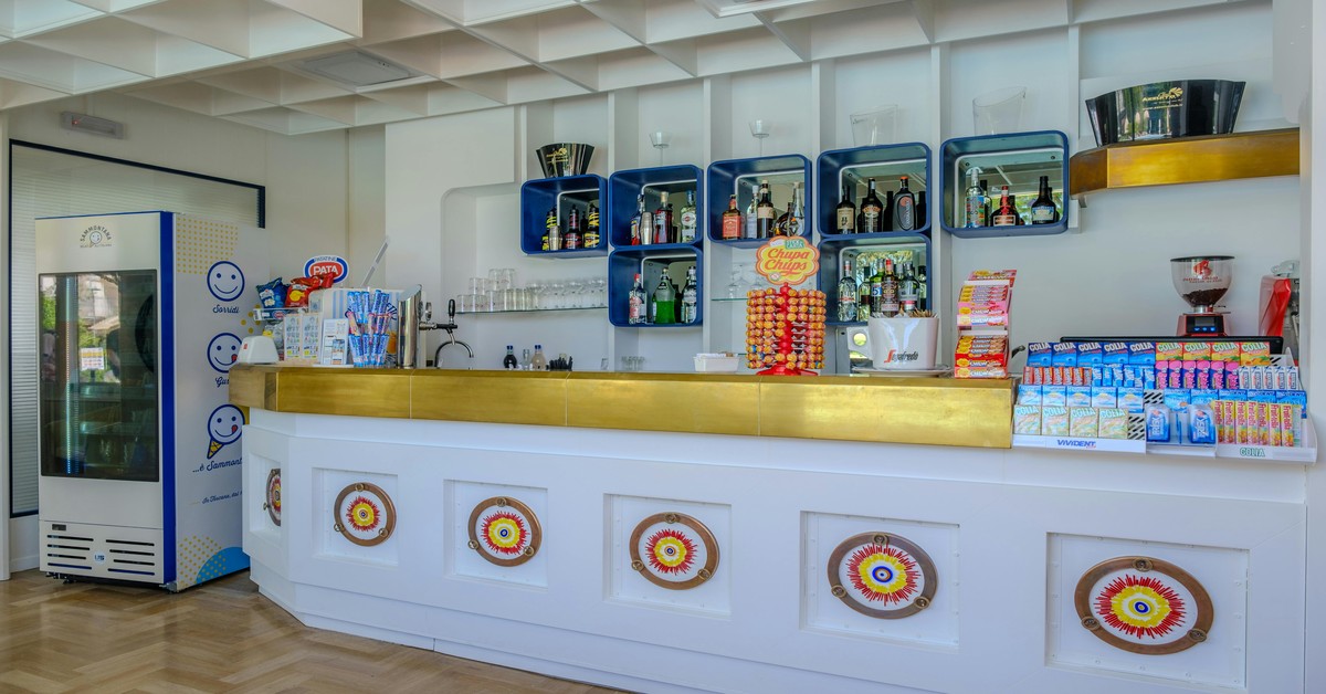 A well-organized hotel mini bar setup on a desk with portable glassware, a shaker, and snacks