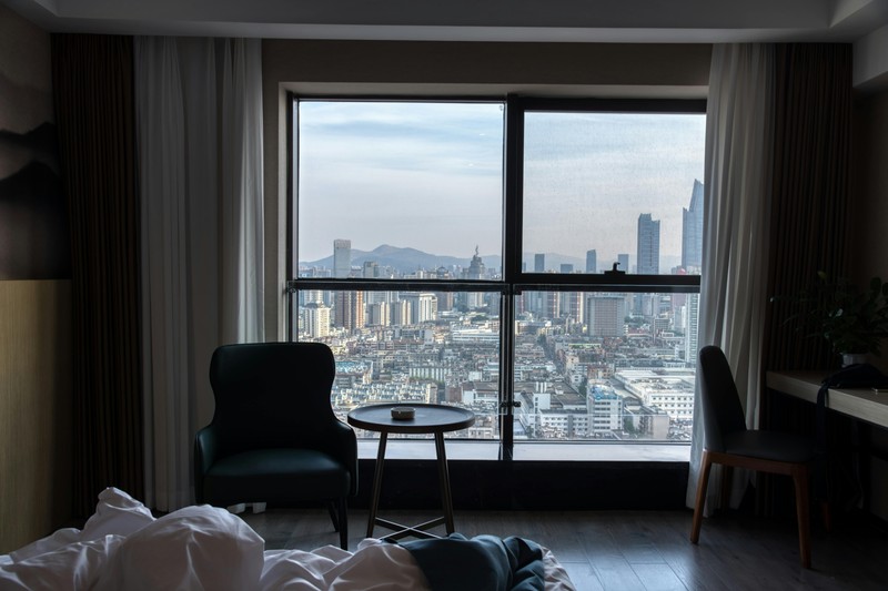 Hotel room with large windows showing a city skyline at night, for a bachelor party