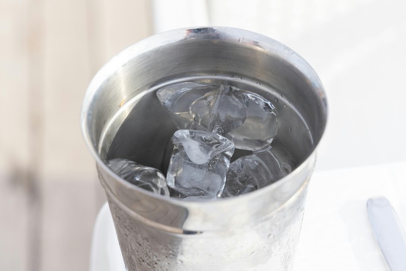 An insulated ice bucket with lid keeping ice cold on a hotel desk