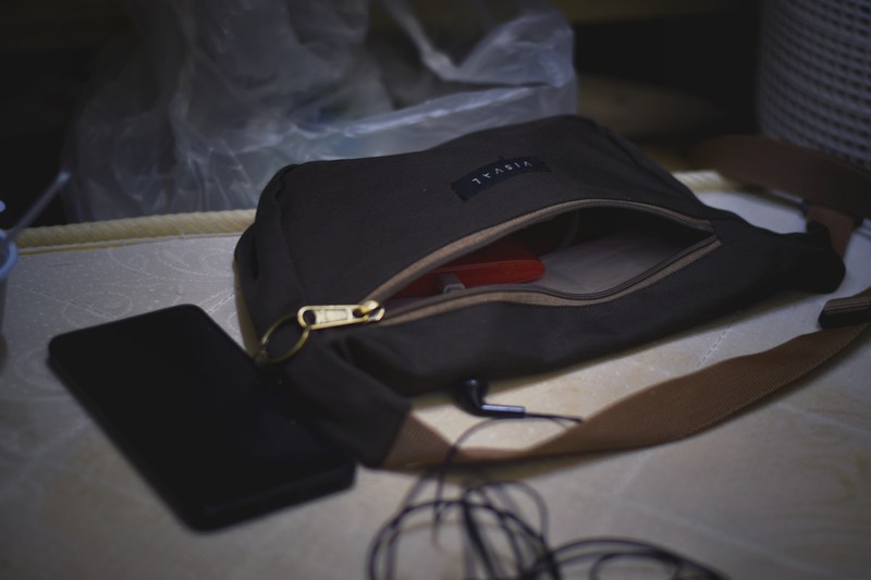Portable phone charger and crossbody bag placed on a wooden table