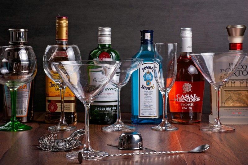 A portable cocktail shaker and stackable stemless wine glasses on a hotel nightstand