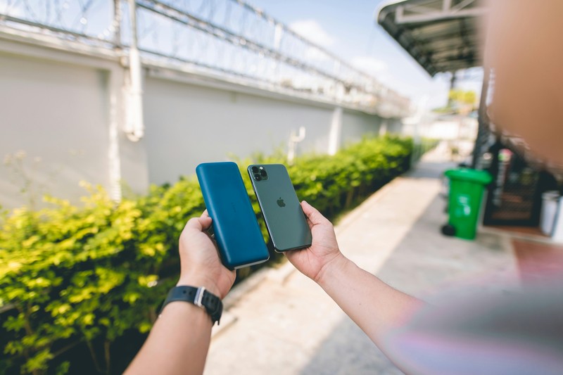 Hands holding a portable power bank charging two smartphones