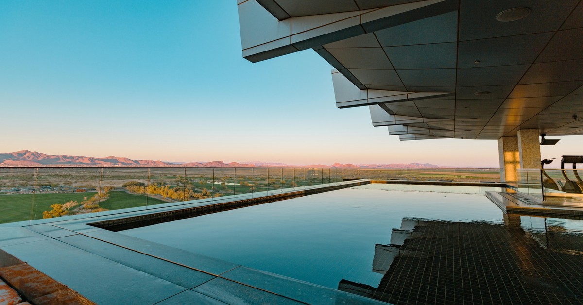 A sprawling Scottsdale resort pool with desert mountains in the background under a clear blue sky
