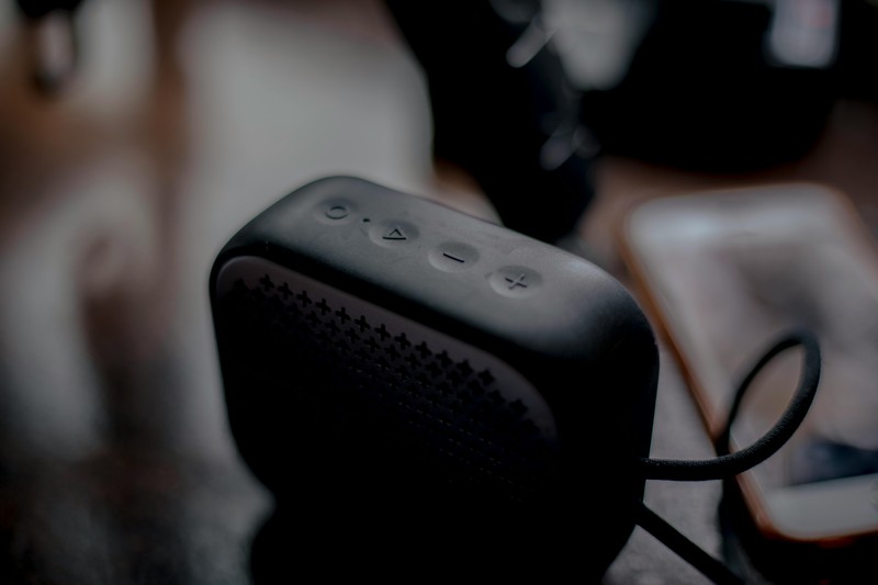 Portable Bluetooth speaker and a small lavalier microphone on a wooden table