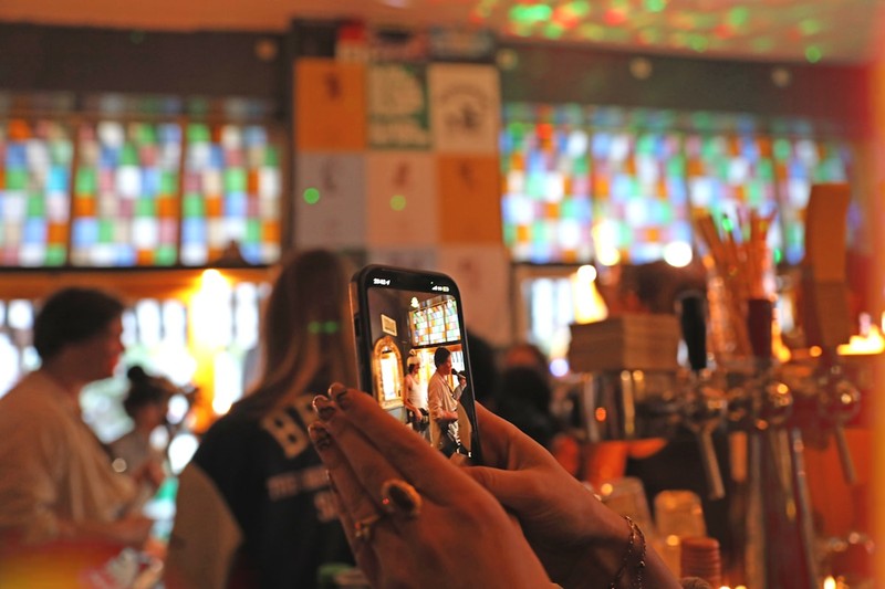 Two friends looking at a smartphone showing a fare-splitting app outside a bar