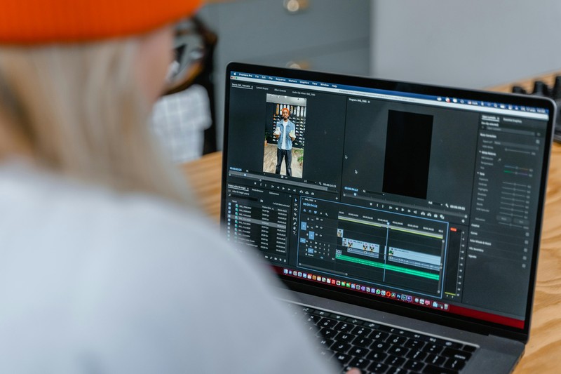 A laptop screen displaying video editing software with a split screen timeline and a montage of travel clips for a bachelor party invitation.